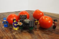 Lego Figuren am Tisch, echte Tomaten im Hintergrund