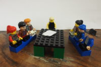 Lego Figuren an einem Tisch sitzend